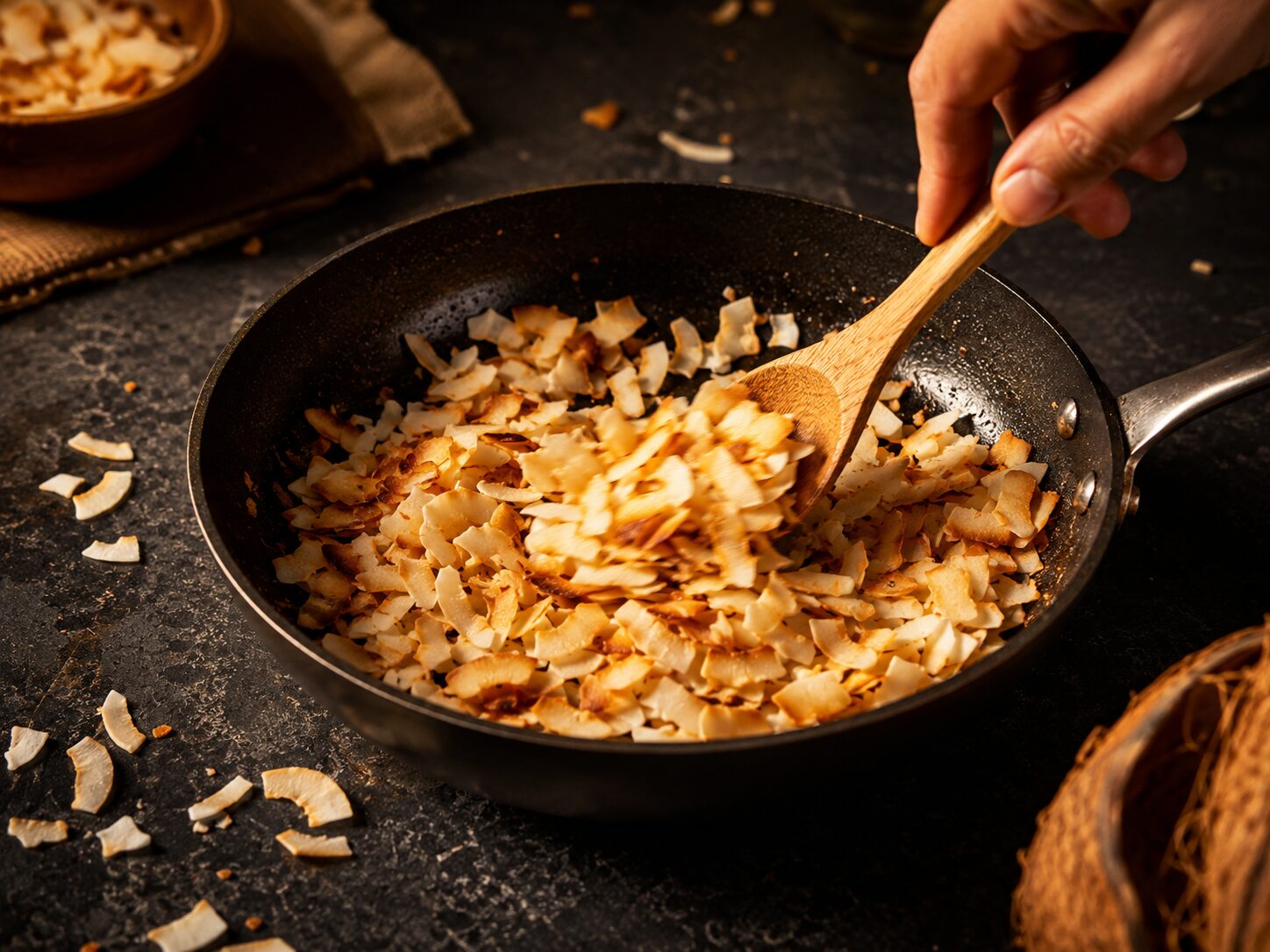 Toasting coconut flakes in a dry frying pan for Dragon Scale Bark