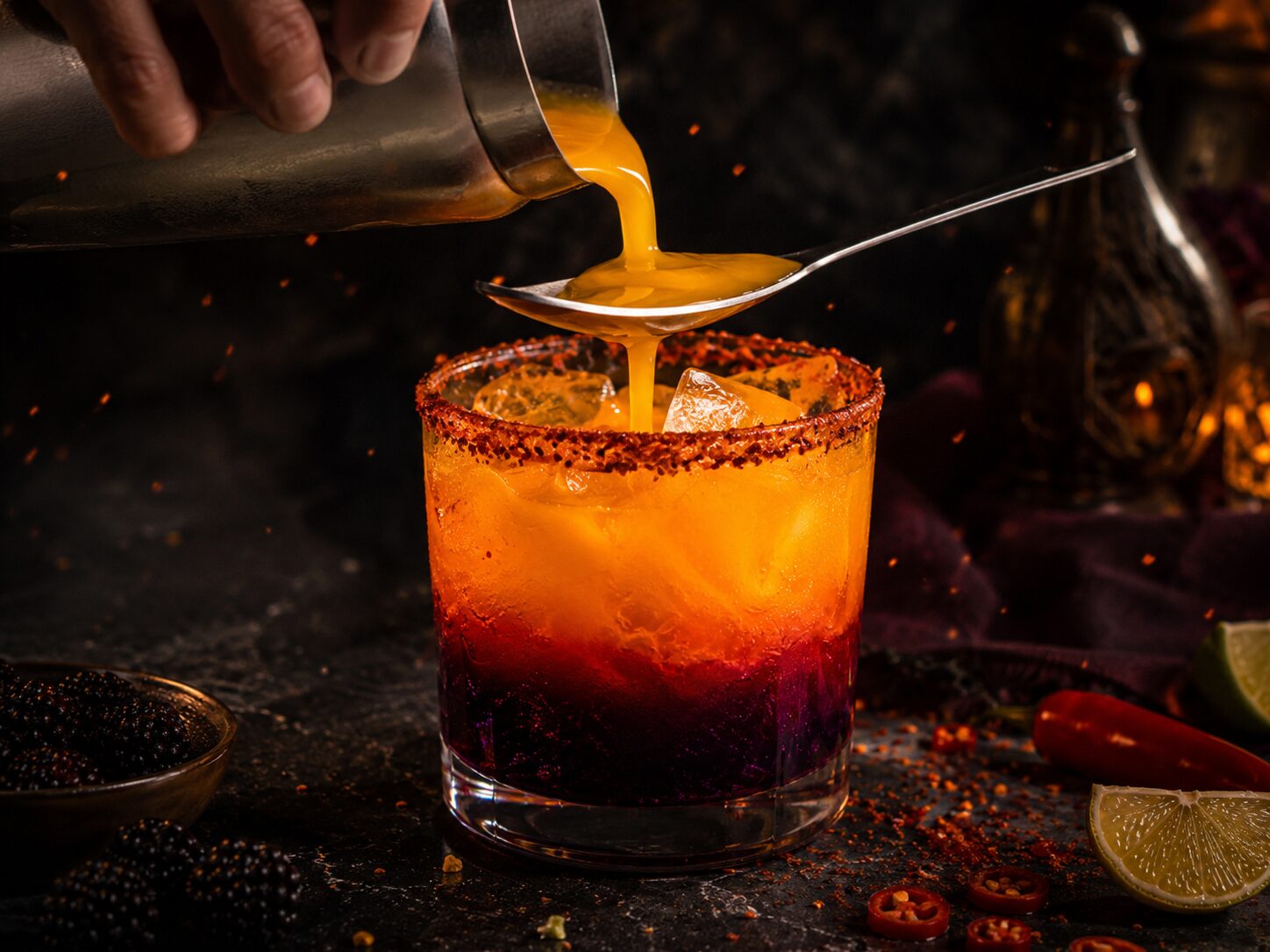 Pouring mango margarita mix over a spoon to create the ember ombre effect