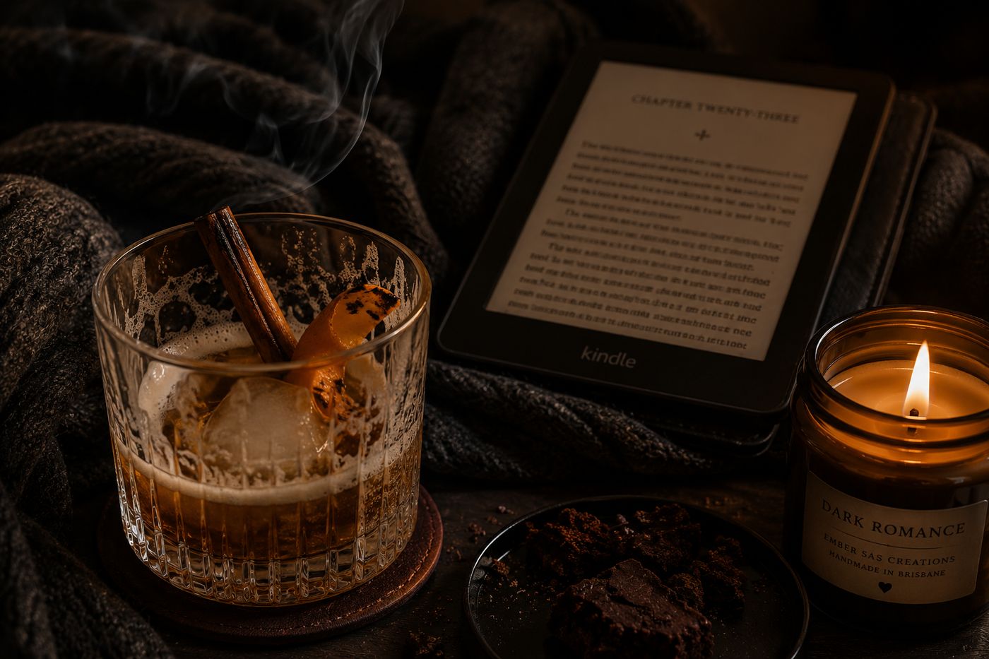 A half finished Outlaw King whiskey sour beside a Kindle and a candle at the end of a reading night