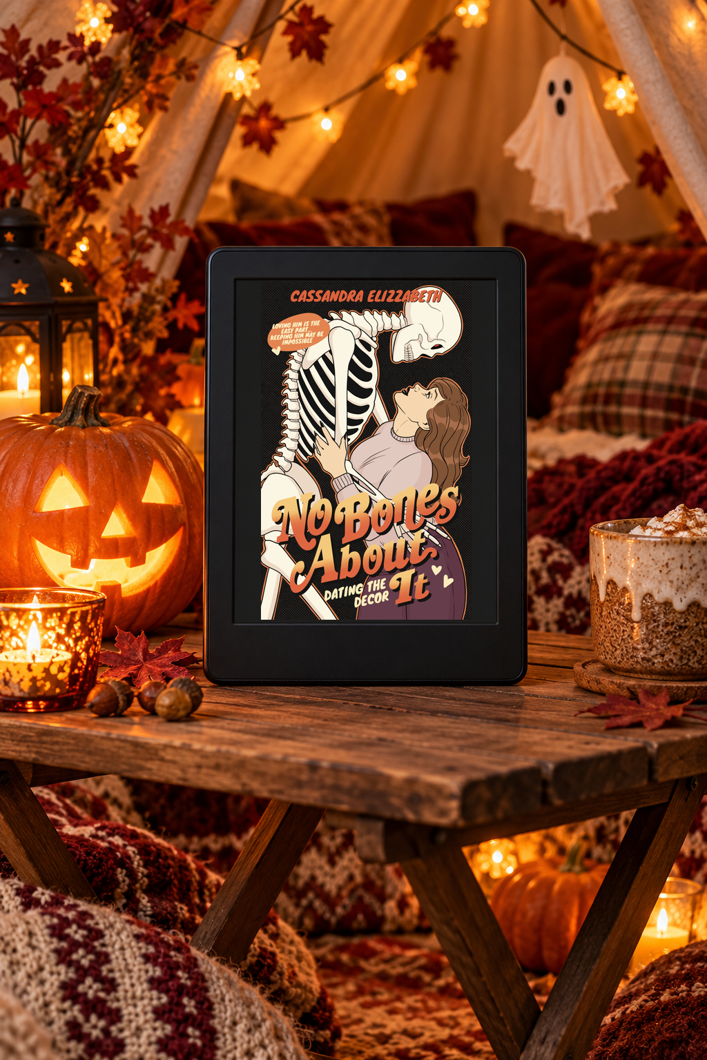 The No Bones About It cover appears intact on a black Kindle beside a glowing pumpkin and cosy tent blankets.